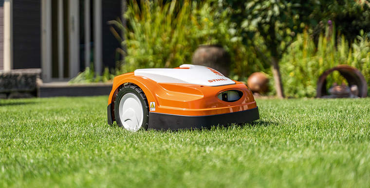 A STIHL iMOW® RMI 422 robot mower on a green lawn in front of a house