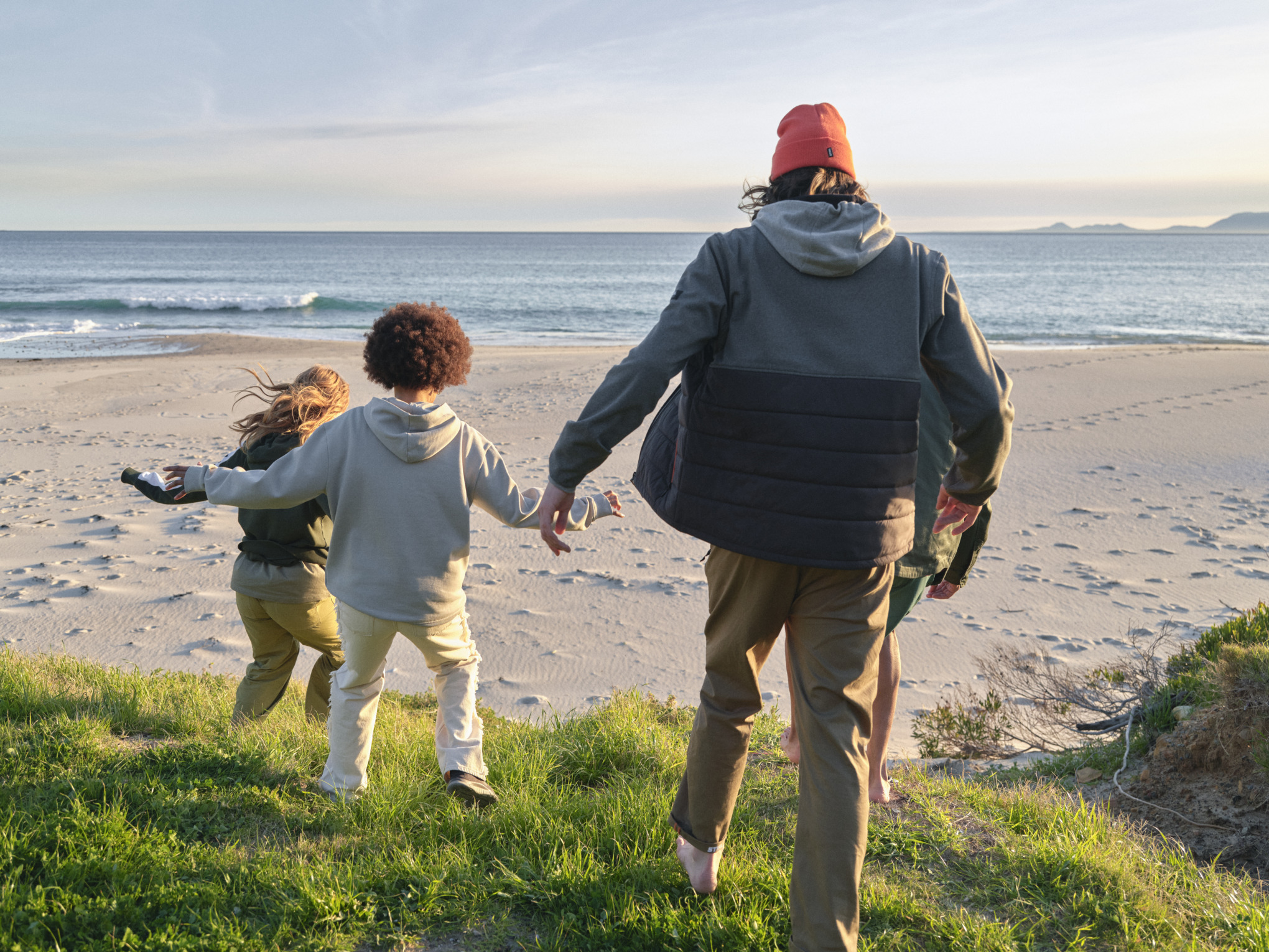 Adult plus children running on the beach