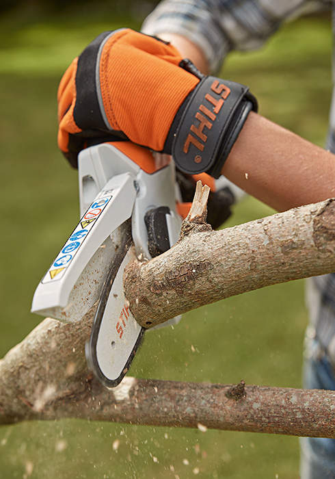 A branch is cut with the STIHL GTA 26 cordless garden pruner, by someone wearing STIHL protective gloves