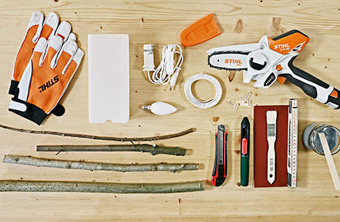 Materials for making a table lamp from twigs: gloves, STIHL GTA 26 cordless garden pruner, branches, and more.
