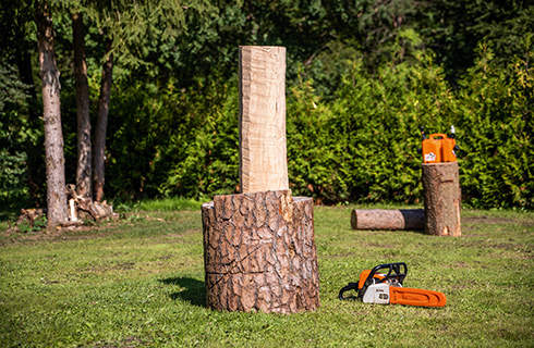 A debarked log on a base, with a STIHL chainsaw on the ground next to it.