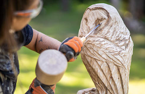 A wooden owl sculpture in progress: fine details are added to the face using a chisel.