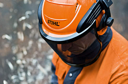 Head and shoulders of a man wearing protective clothing and a STIHL helmet set with face protection