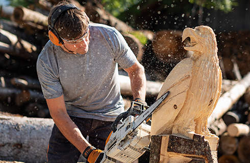 A man making an eagle sculpture from a log using a STIHL MSE 193 CE petrol chainsaw with carving guide bar