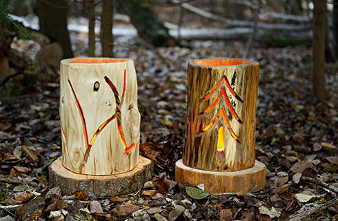 Light shines through the patterns carved into two DIY log lanterns