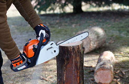 A STIHL MS 181 petrol chainsaw being used to make a vertical cut in an upright log