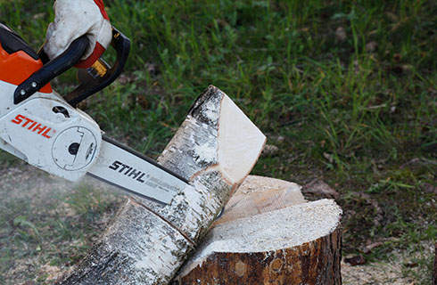 DIY wooden candlesticks: A STIHL MSA 140 C chainsaw being used to carve a flame shape into a log
