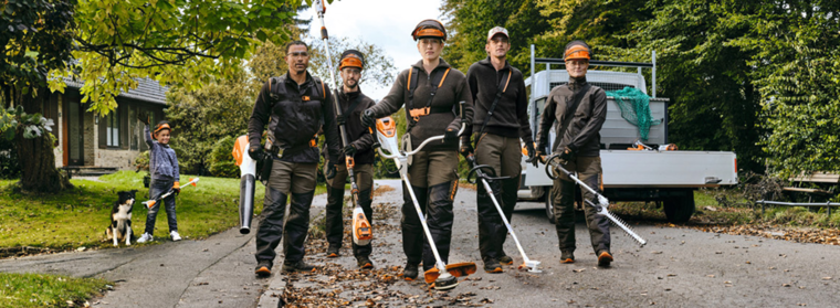 A gardening and landscaping team with STIHL professional cordless power tools walking along a street.