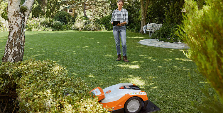 A STIHL iMOW® RMI 632 robot mower in its charging station in a garden.